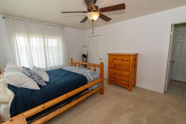 bedroom with light colored carpet, ceiling fan, and a closet