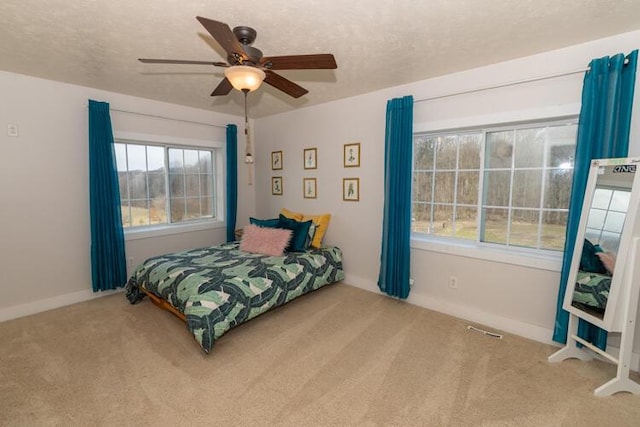 bedroom with ceiling fan, multiple windows, carpet, and a textured ceiling