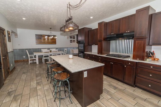 kitchen with decorative light fixtures, a textured ceiling, stainless steel gas cooktop, and a center island