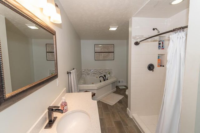 full bathroom featuring toilet, a textured ceiling, separate shower and tub, and vanity