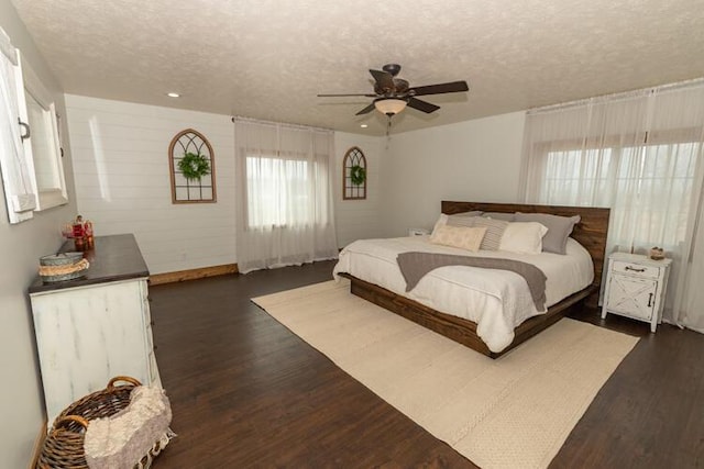 bedroom featuring a textured ceiling, multiple windows, ceiling fan, and dark hardwood / wood-style floors