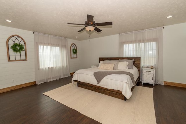 bedroom featuring dark hardwood / wood-style flooring, a textured ceiling, ceiling fan, and multiple windows