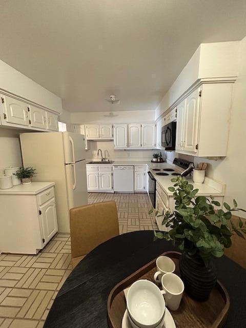 kitchen with white appliances, sink, and white cabinetry