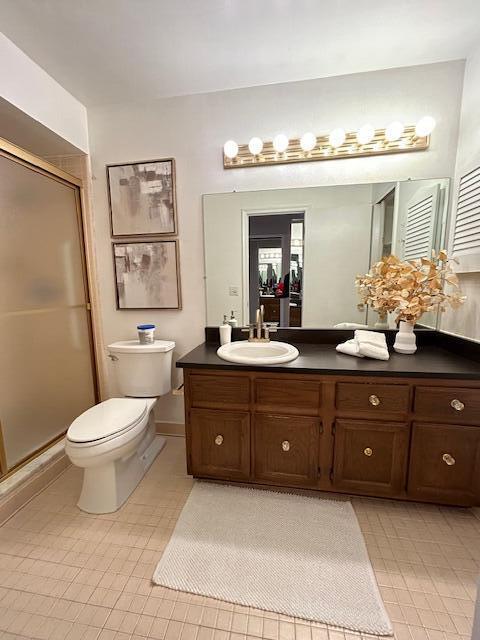 bathroom featuring toilet, a shower with shower door, and vanity