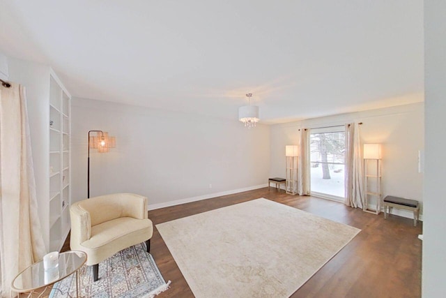 sitting room with built in shelves, a notable chandelier, and dark hardwood / wood-style floors