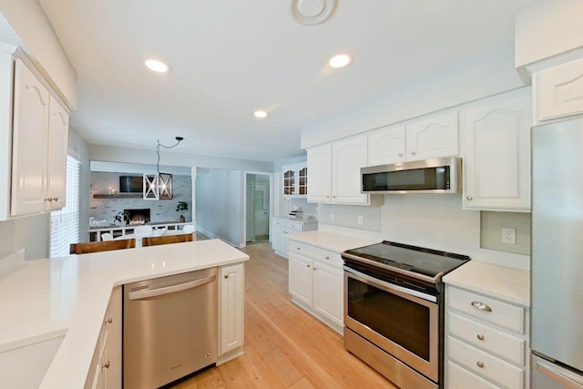 kitchen with light hardwood / wood-style floors, stainless steel appliances, hanging light fixtures, a notable chandelier, and white cabinets