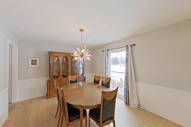 dining space with light hardwood / wood-style flooring and an inviting chandelier