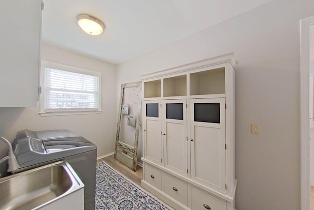 clothes washing area with sink, cabinets, washer / clothes dryer, and light hardwood / wood-style floors