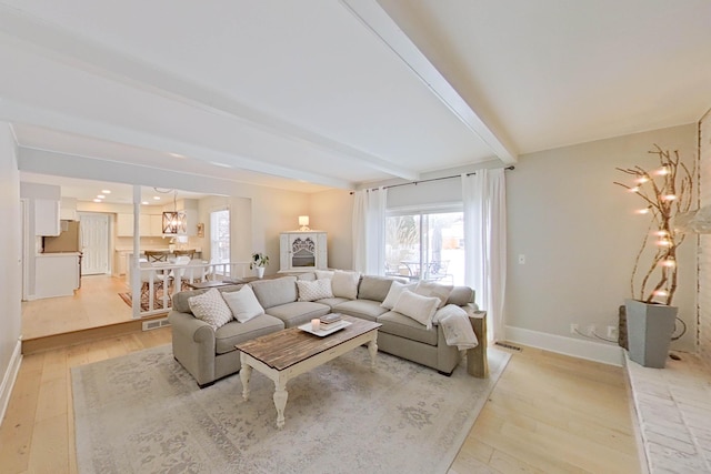 living room featuring a chandelier, light hardwood / wood-style floors, and beamed ceiling