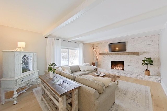 living room with light wood-type flooring, beamed ceiling, and a fireplace