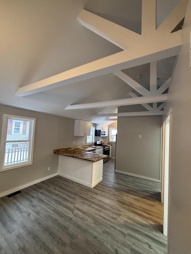 kitchen with vaulted ceiling with beams, kitchen peninsula, white cabinetry, stainless steel range, and dark wood-type flooring