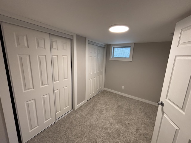 unfurnished bedroom featuring light colored carpet and multiple closets