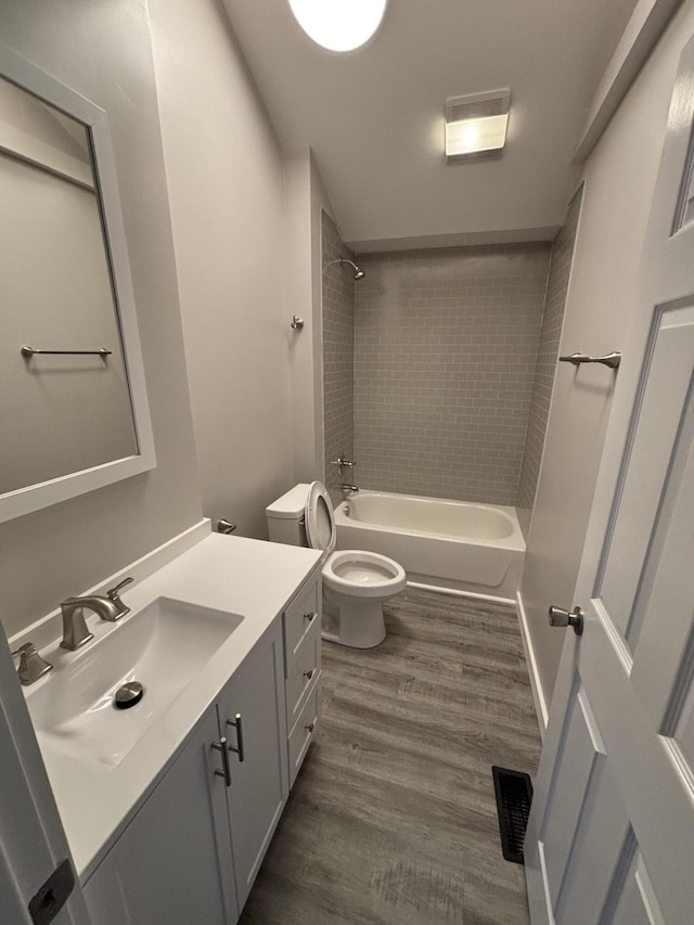 full bathroom with wood-type flooring, toilet, vanity, and tiled shower / bath