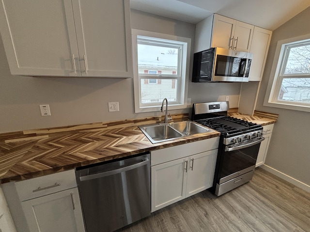 kitchen with appliances with stainless steel finishes, a healthy amount of sunlight, white cabinets, and sink