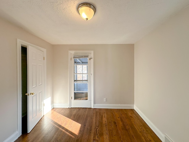 empty room with a textured ceiling and dark hardwood / wood-style floors