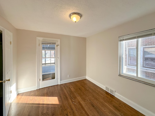 unfurnished room featuring a textured ceiling and dark hardwood / wood-style floors