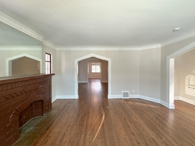 unfurnished living room featuring a brick fireplace, ornamental molding, and dark hardwood / wood-style floors