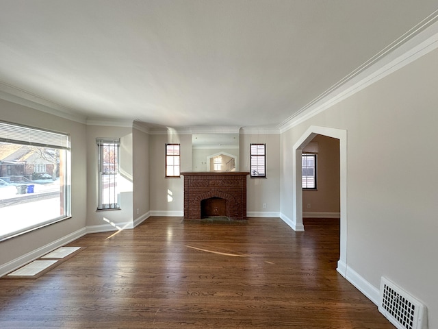 unfurnished living room with crown molding, dark hardwood / wood-style flooring, a healthy amount of sunlight, and a fireplace