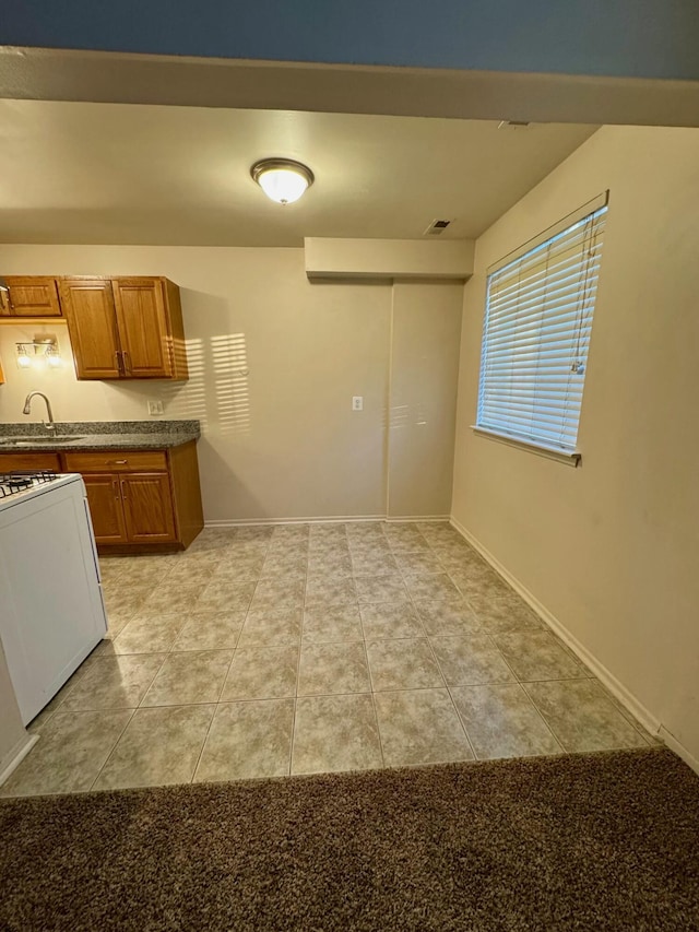 kitchen featuring sink, white gas stove, and light tile patterned floors