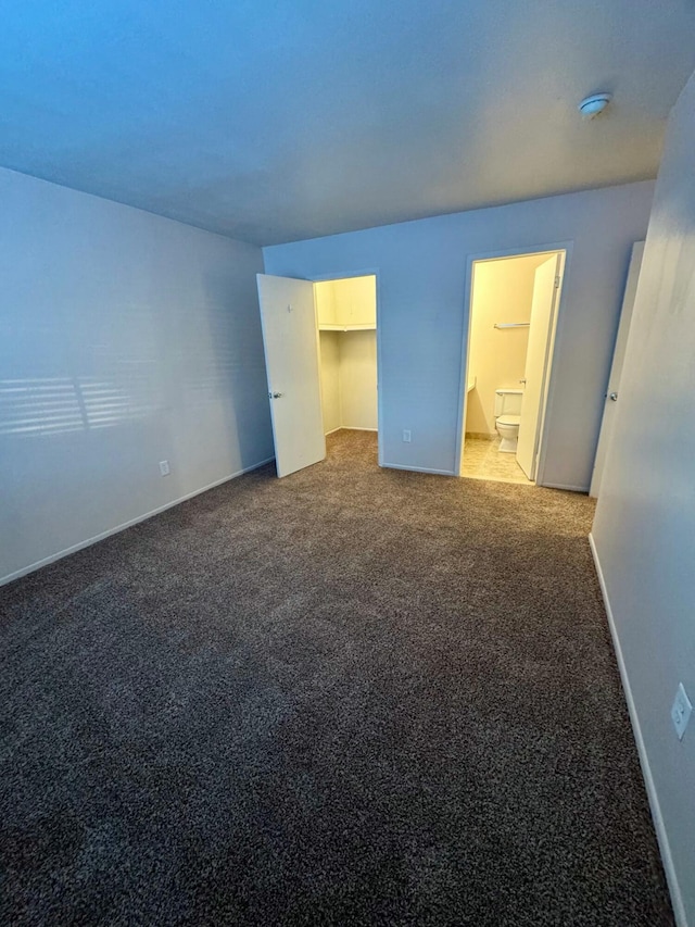 unfurnished bedroom featuring ensuite bathroom, a closet, and light carpet