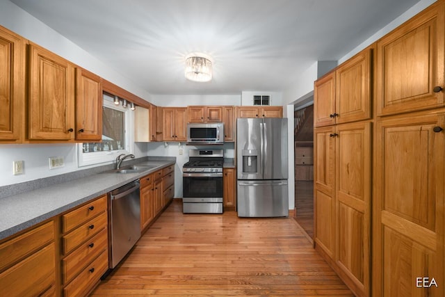 kitchen with appliances with stainless steel finishes, sink, and light hardwood / wood-style floors