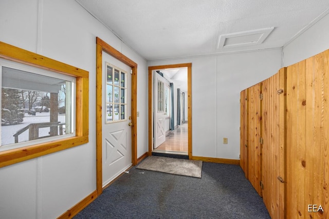 doorway to outside with a textured ceiling and dark colored carpet