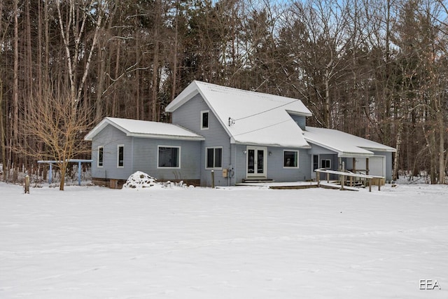 snow covered back of property featuring a garage