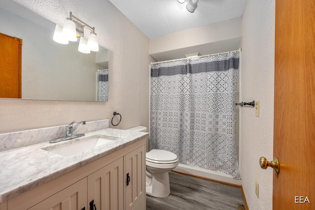 bathroom featuring toilet, vanity, hardwood / wood-style floors, a shower with curtain, and a textured ceiling