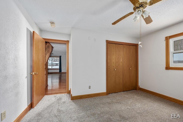 unfurnished bedroom with ceiling fan, light colored carpet, a closet, and a textured ceiling