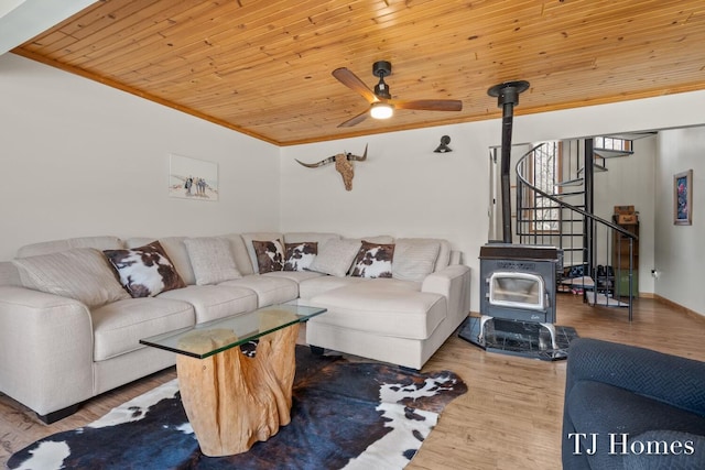 living room with wood ceiling, ceiling fan, wood-type flooring, ornamental molding, and a wood stove