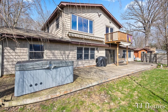 rear view of property with a wooden deck and a hot tub