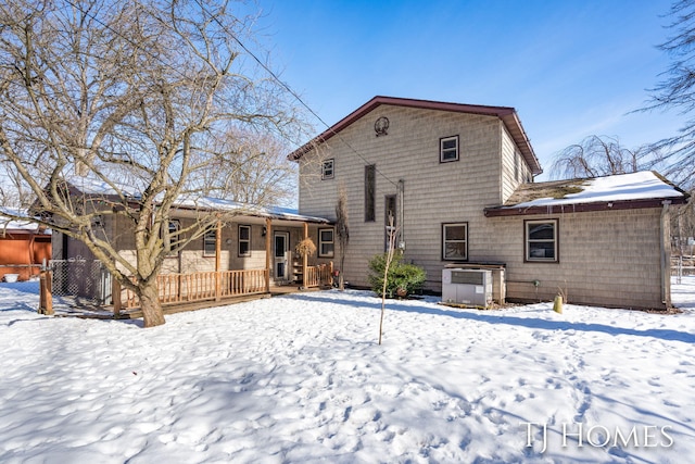 snow covered back of property featuring a deck