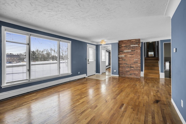 spare room featuring a textured ceiling, hardwood / wood-style flooring, and a baseboard heating unit