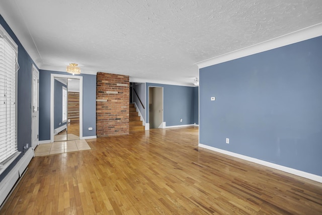 empty room featuring hardwood / wood-style flooring, a textured ceiling, and baseboard heating