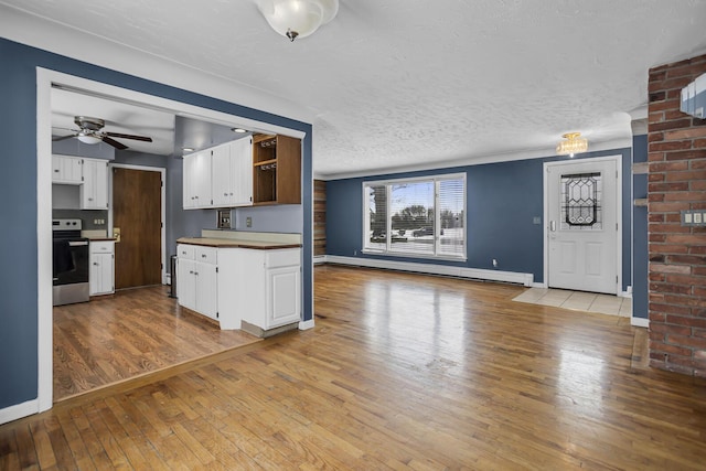 kitchen with electric range, light wood-type flooring, ceiling fan, white cabinets, and a baseboard radiator