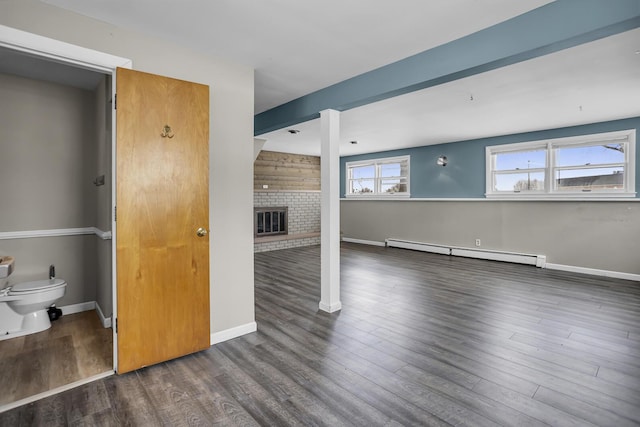 interior space featuring a brick fireplace, a baseboard heating unit, and dark wood-type flooring