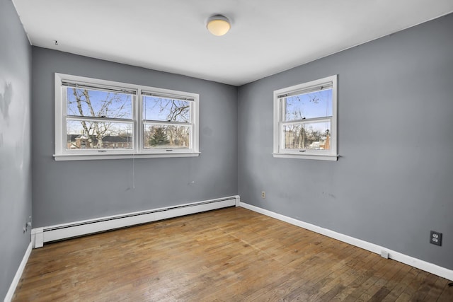 spare room with wood-type flooring and a baseboard heating unit