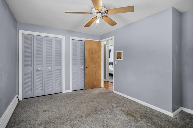 unfurnished bedroom featuring a baseboard heating unit, two closets, ceiling fan, and carpet