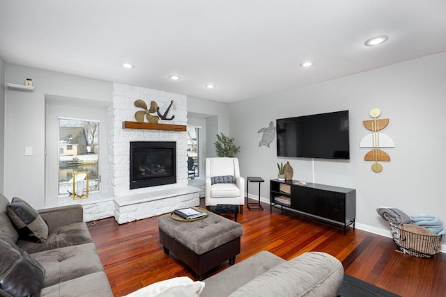 living room featuring a stone fireplace and dark hardwood / wood-style flooring