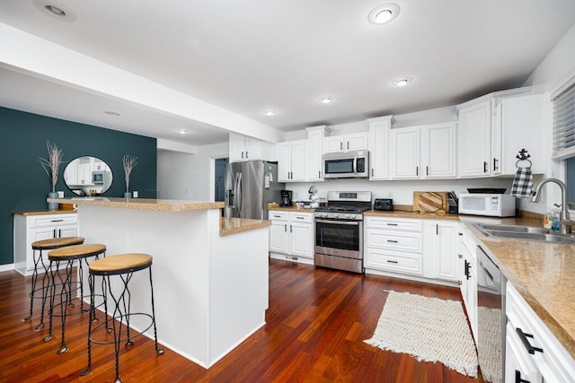 kitchen featuring sink, a breakfast bar area, a kitchen island, stainless steel appliances, and white cabinets