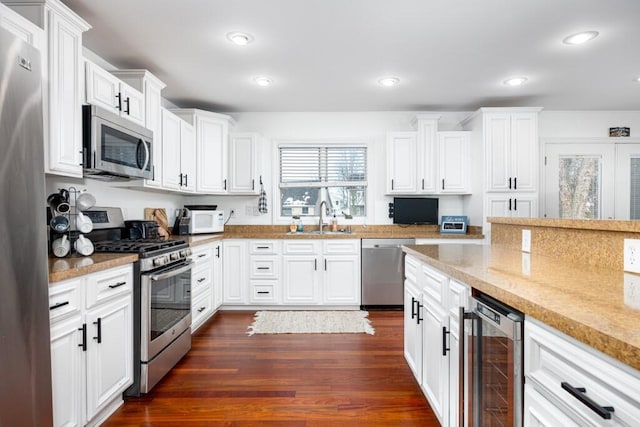 kitchen with stainless steel appliances, sink, white cabinets, and wine cooler