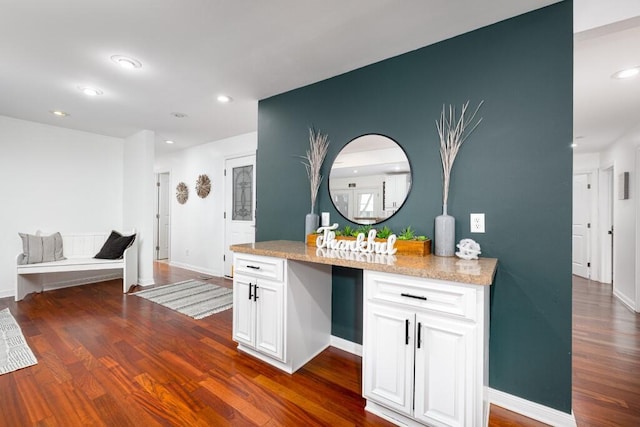 kitchen featuring dark hardwood / wood-style flooring, light stone counters, and white cabinets