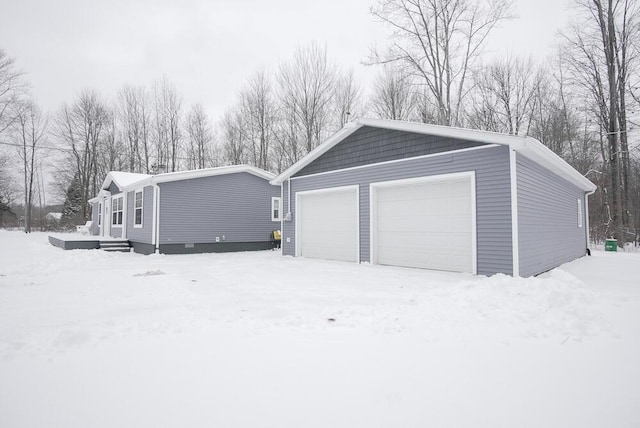 snow covered property with a garage and an outdoor structure