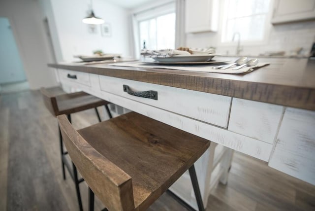 kitchen with decorative light fixtures, dark wood-type flooring, and white cabinetry