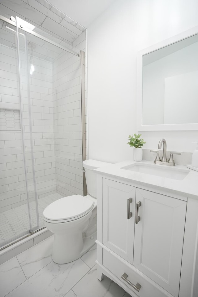 bathroom featuring toilet, an enclosed shower, and vanity