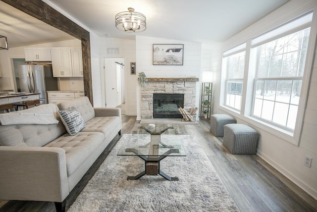 living room featuring a chandelier, vaulted ceiling, wood-type flooring, and plenty of natural light