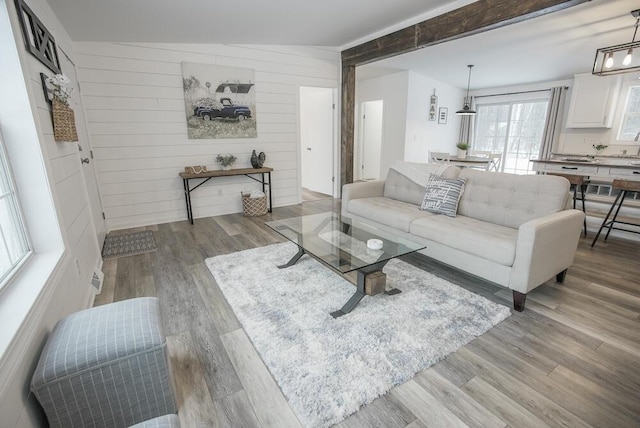 living room with wood walls, vaulted ceiling, and light hardwood / wood-style floors