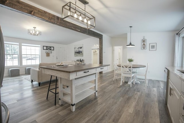 kitchen featuring white cabinets, a kitchen bar, stainless steel dishwasher, dark hardwood / wood-style flooring, and pendant lighting