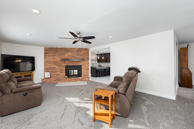 living room with a brick fireplace, carpet flooring, and ceiling fan