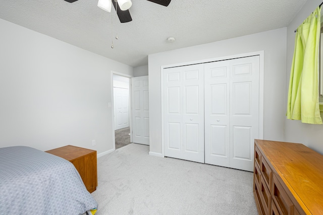 carpeted bedroom with ceiling fan, a textured ceiling, and a closet